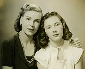 Mother with arm on daughters (10-11) shoulder, (B&W), portrait