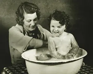 Basin Prints: Mother bathing daughter (12-18 months) in basin, (B&W)