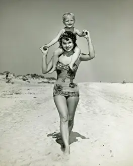 30 35 Years Prints: Mother carrying son (2-3) on shoulders, walking on beach, (B&W), portrait