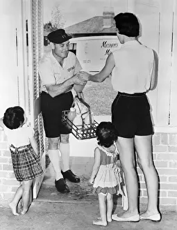 Delivery Prints: Mother with two children (3-4 years) paying milkman in doorway