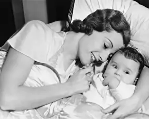 Wavy Hair Prints: Mother cuddling baby boy (6-12 months), lying on bed, , (B&W), close-up