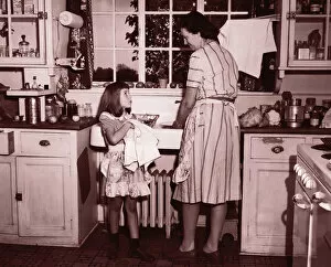 Mother and daughter (8-10) washing and wiping dishes (B&W sepia tone)
