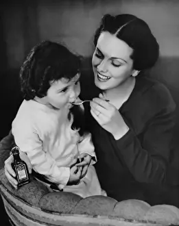 Mother giving spoon of medicine to child