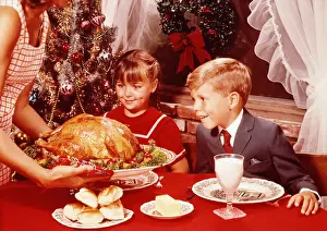 Mother showing roast turkey to children (7-10) at Christmas meal