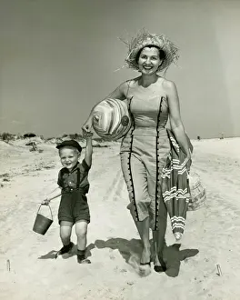 Preschooler Prints: Mother with son (2-3) walking on beach, (B&W), portrait