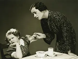 Problem Prints: Mother trying to make daughter (4-5) finish food at table, (B&W)