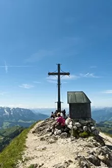 Mountain climber at the summit cross with a small chapel on Geigelstein Mountain, 1808 m, Geigelstein Nature Reserve
