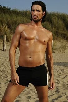 Desire Gallery: Muscular man wearing swimming trunks posing on beach