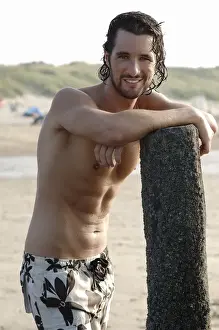 Suit Prints: Muscular man wearing swimming trunks standing on a beach