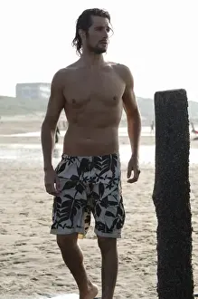 Athleticism Prints: Muscular man wearing swimming trunks standing on a beach