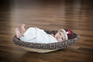 Newborn baby, 3 weeks, wearing a hat, lying in a basket