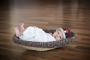 Images Dated 29th January 2011: Newborn baby, 3 weeks, wearing a hat, lying in a basket