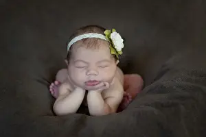 Newborn baby, five days, asleep with head propped up on hands