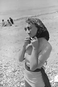 Prints of 8th October 1938: A woman protecting herself from the sun on the beach at Shoreham, West Sussex. Original Publication: Picture Post - 12 - A Day With Gordon Richards - pub Chronicling Britain's Story in Pictures: Nose Protection