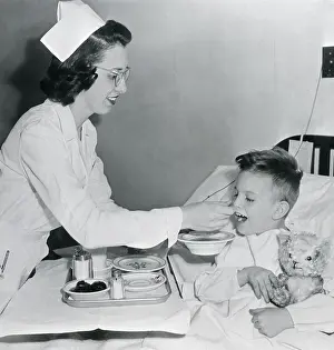 Nurse Feeding Boy in Bed