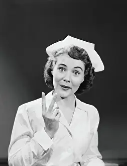 One Mid Adult Woman Only Prints: Nurse holding up two fingers signifying arrival of twin babies, portrait