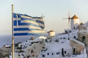 Images Dated 25th August 2012: Oia village in Santorini and flag of Greece