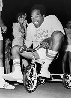 O.J. Simpson Pedaling a Tricycle