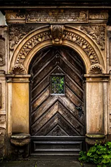 An old carved wooden door with an ornate frame with latin inscriptions