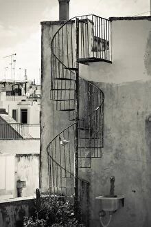 Old cast iron spiral staircase accessing a rooftop terrace in Otranto, Apulia, Italy