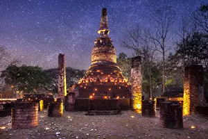 Old stupa with candlelight and milky way galaxy in the Kamphaeng Phet Historical Park