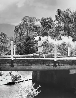 Prints of A torch bearer carries the Olympic flame across a bridge as he passes through the Australian countryside soon after leaving Mackay on the northeast coast, November 18th 1956 Bettmann Archive Prints: Olympic Torch In Australia