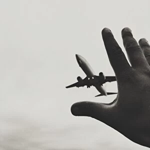 Images Dated 13th July 2014: Optical Illusion Of Hand Reaching Airplane Against Sky
