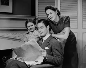 Two Parents Prints: Parents with daughter (6-7 years) reading newspaper together