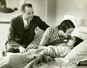 40 49 Years Prints: Parents tucking daughter (6-7) into bed, (B&W)