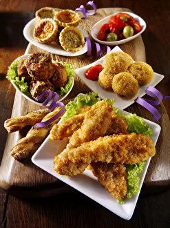 Party buffet food with Southern fried chicken, onion balls, small quiches and fried Camembert