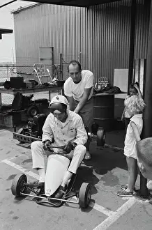 Prints of American actor Paul Newman, his crash helmet partially obscuring his face, as a man lifts the rear wheels of Newman's go-kart off the ground, watched by young children, at the Go Kart Raceway Paul Newman: A Life in Frames: Paul Newman, Go Kart Raceway, Azusa, California