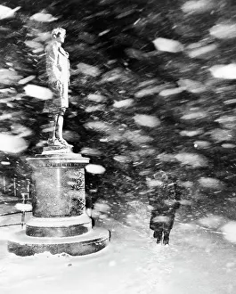 Snowfall Prints: Pedestrian Passing Statue in Snow Storm