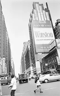 Pedestrians Crossing Street near Large Advertisement on Cigarettes