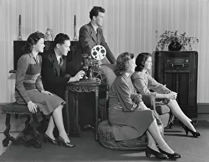 Embracing Prints: Five people watching home movies, seated around projector, looking toward screen