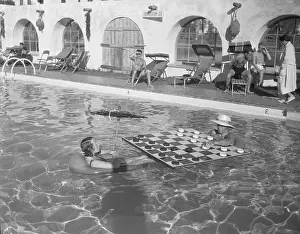 Performers with Large Checker Board in Swimming Pool