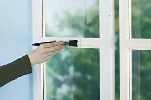 Person painting window frame with a brush