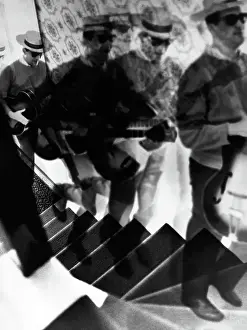 Prints of NEW YORK - 1960: An artistic photo montage (created in the darkroom by layering negatives together) of a man climbing a staircase while serenading and playing the guitar, in 1960 in New York City Portraits, Artworks, and Montages from a Visionary Photographer: Photo Montage of Serenading Man Climbing Stairs in 1960's