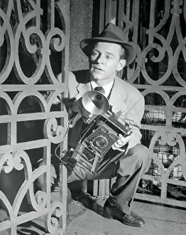 Paparazzi Prints: Photographer Crouching Behind Gate