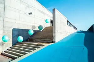 Poetic stop motion picture of green balloons following each other going up on stairs in a