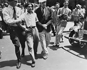 Photojournalist Prints: Policeman Escorting Man