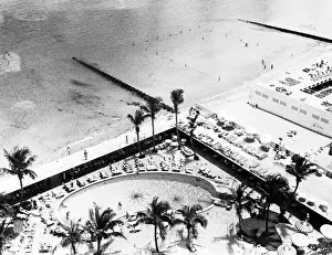 Prints of Birds eye view of vacationers and tourists as they sunbathe by the swimming pool adjacent to the beach at the Sans Souci Hotel (built 1949), Miami Beach, Florida, 1950s Black and White Images Capturing the Essence of Mid-20th Century: The Pool At The Sans Souci