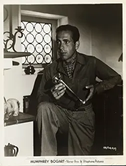 Prints of Publicity handout of Warner Brothers and Vitaphone Pictures film star Humphrey Bogart (1899-1957). Bogart is shown holding a metal cup and a cigarette. Undated publicity handout The Essence of Cool: Portrait of Actor Humphrey Bogart