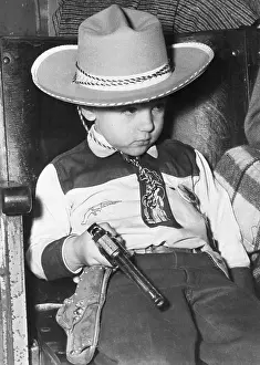 Portrait of boy (4-5) in cowboy costume holding pistol