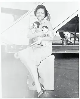 Prints of (Original Caption). Eartha Kitt cuddles momentos of her round-the-world trip after arriving here Captivating Art Prints Celebrating the Iconic Performer’s Legacy: Portrait of Eartha Kitt