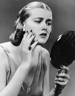Portrait of upset woman looking in hand mirror