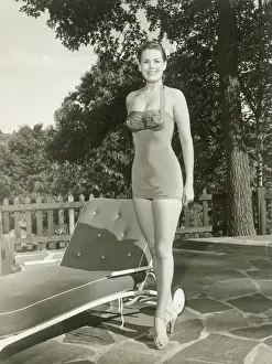 Portrait of young woman by lounge chair in garden