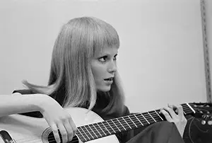 Profile of Mia Farrow Sitting on Street Playing Guitar