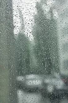 Raindrop Gallery: Rain drops on a window pane, blurry buildings and cars in the back