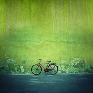 Red vintage bike against a green flaking plaster wall