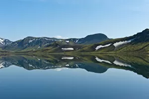 Reflection in the still lake, remnants of snow, panoramic mountain landscape at Alftavatn lake